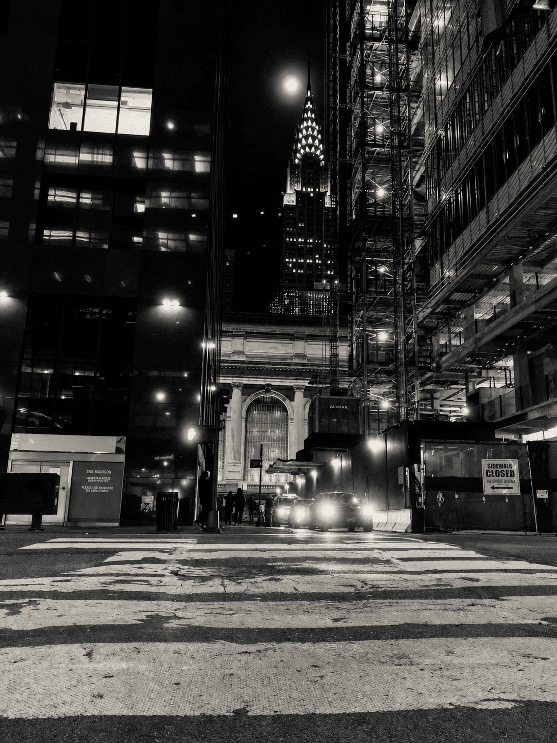 Black and white night view of the Chrysler Building spire rising above Grand Central Terminal.